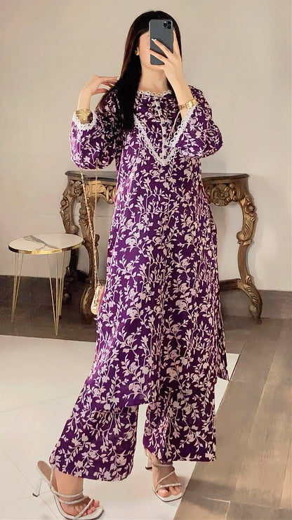 Person wearing a purple floral dress taking a mirror selfie in a room with a table and chair.